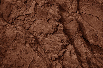 Red brown rock texture. Cracked layered mountain surface. Close-up. Grungy stone background with space for design.