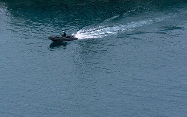 A motor boat leaving port on a spring morning. The blue sea and the waves left by the boat's engine