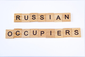 Top view of the words russian occupiers laid out from square wooden tiles isolated on white background.Concept of russian army, war in Ukraine, no war,support ukraine