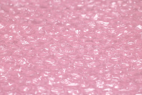 Pink background of polymer packaging material, layers of smooth and bubble polyethylene, bubble wrap