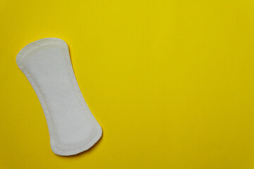 Close-up image of a women's sanitary napkin on a yellow background leaving copy space. Concept of intimate hygiene of the woman when she is with the period.