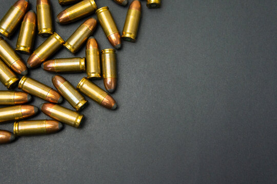 A bunch of gun bullets stacked up in one corner forming a beautiful black background wallpaper. Firearm cartridges placed in a corner leaving copy space.