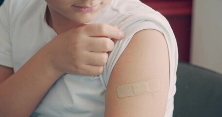 A boy getting vaccinated at the Pediatrician's office. Kid is sitting. Young boy shows his hand to doctor.