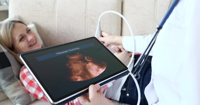 Pregnant woman doing obstetric sonogram with ultrasound equipment at home