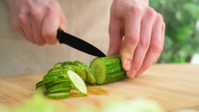 Caucasian man cutting fresh cucumber