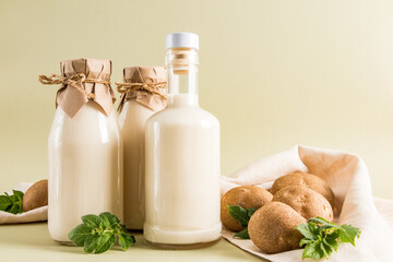 delicious healthy potato milk in glass bottles on a beige pastel background. close angle. source of iron, vitamin C.