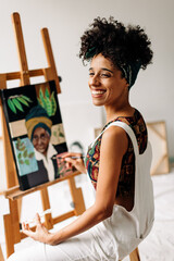 Cheerful young woman painting in her art studio