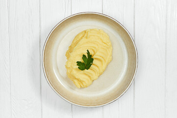 Mashed potatoes in a plate on a white wooden background