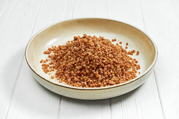 Buckwheat porridge in a plate on a white wooden background