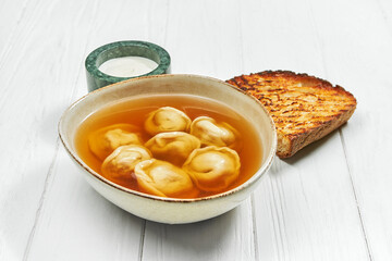 Soup with dumplings in a plate on a white wooden background