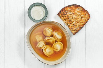 Soup with dumplings in a plate on a white wooden background