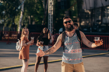 Group of friends drinking beer and having fun at music festival