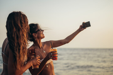 Friends enjoying vacation together and taking selfie on the beach using smartphone