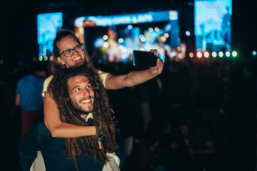 Fototapeta na wymiar Couple taking selfie with a smartphone on a music festival