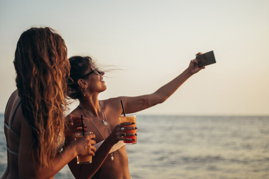 Friends enjoying vacation together and taking selfie on the beach using smartphone