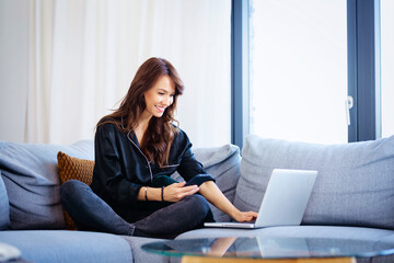 Attractive brunette haired woman using her mobile phone and laptop while working from home