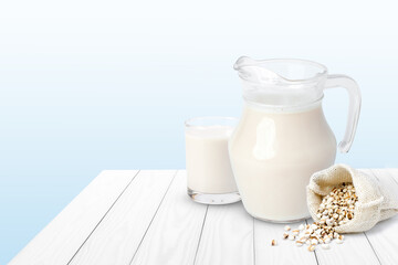 Glass jug of job's tears milk and millet seeds isolated on wooden table.