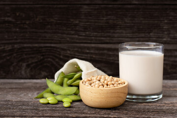 Glass of soy milk with soybean in wooden bowl isolated on rustic wooden table background. 