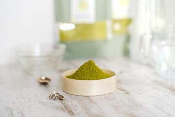Green herbal detox powder in a plate on wooden table. Superfood. Organic eco health care. Vitamin nutrition and treatment. Immune system support. Alternative medicine. Dietary supplement, bowel clean.