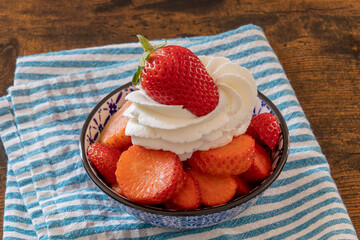 bowl of strawberry with whipped cream on wooden table