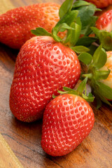 whole red strawberries isolated on a wooden background