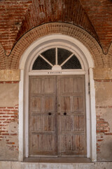 Ancient wooden door with lock in old stone wall.