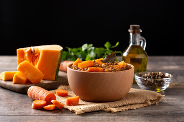 Lentil stew ragout with pumpkin and carrot in bowl on wooden table