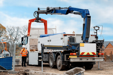 Dropside flatbed HIAB crane lorry with brick grab attachment deliver materials on construction site...