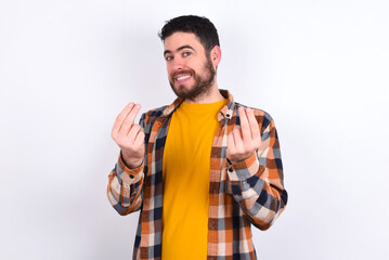 young caucasian man wearing plaid shirt over white background, making money gesture.