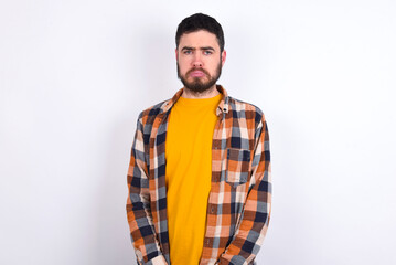 Fototapeta premium young caucasian man wearing plaid shirt over white background crying desperate and depressed with tears on his eyes suffering pain and depression. Sad facial expression and emotion concept.