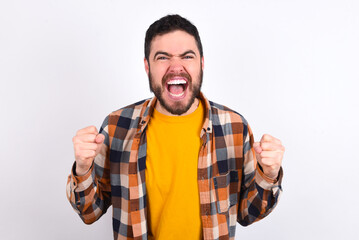Portrait of young caucasian man wearing plaid shirt over white background looks with excitement at...