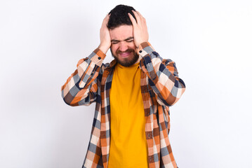young caucasian man wearing plaid shirt over white background holding head with hands, suffering from severe headache, pressing fingers to temples