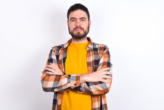 Picture of angry young caucasian man wearing plaid shirt over white background looking camera.