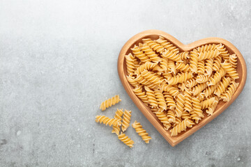 Pasta in a heart shaped wood bowl.