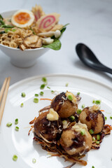 A bowl of Ramen soup an a plate of Takoyaki snack