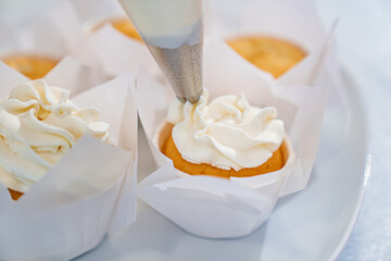 close-up. cupcakes are decorated with white cream from a cooking bag. 