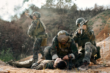 responsive army soldiers with injured comrade calling for help, blowing smoke, marines team in...