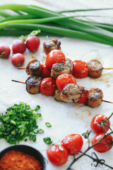 Shashlik or shish kebab prepared on barbecue grill over hot charcoal with grilled vegetables. Grilled pieces of pork meat on metal skewers.