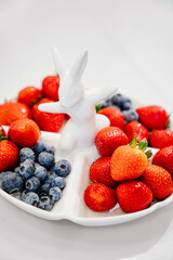 strawberries and blueberries in a white compartmental dish with rabbit. 
