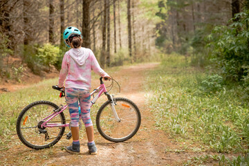 happy child girl riding a bike on natural background, forest or park. healthy lifestyle, family day...