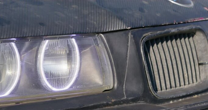 Black tuned drift car headlights on hood and radiator screen located on bumper and automobile parked AT marked track in city closeup