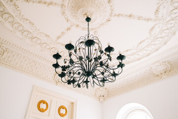 Beautiful vintage chandelier in the living room with ornamental ceiling.