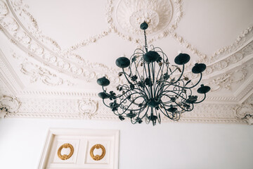 Beautiful vintage chandelier in the living room with ornamental ceiling.