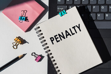 PENALTY text on white notepad on office background with pencil, staples, notes and keyboard around.