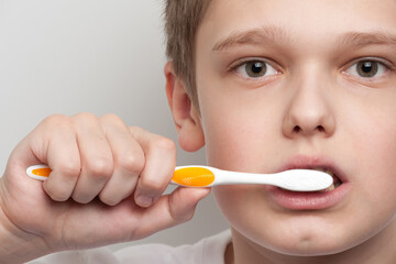 Boy's face and hand holding a toothbrush near his mouth. Dental and oral hygiene