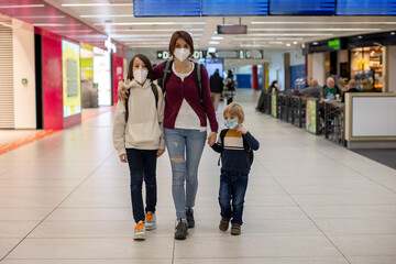 Fototapeta premium Cute baby boy waiting boarding to flight in airport transit hall near departure gate. Active family lifestyle travel by air with children