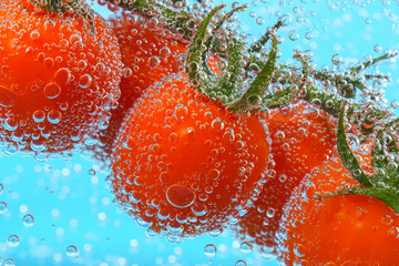 Red tomato close-up under water. Juicy vegetable with a bubble on blue background.