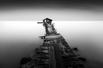 Beautiful scenery of an old wooden pier in a minimalist fine art with the view of the sunrise in black and white