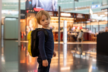 Cute  baby boy waiting boarding to flight in airport transit hall near departure gate. Active family lifestyle travel by air with children