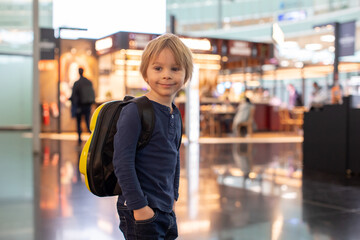 Cute  baby boy waiting boarding to flight in airport transit hall near departure gate. Active family lifestyle travel by air with children